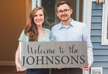 Young Happy Couple Holding Custom Engraved Stainless Steel Welcome Sign.