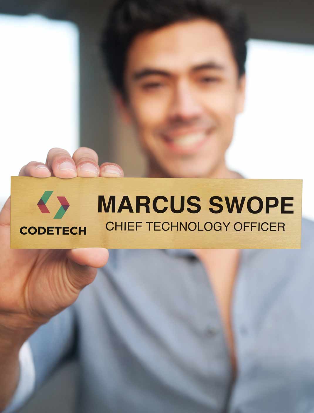 Man holding a custom aluminum nameplate with 'Marcus Swope' and 'Chief Technology Officer' at Codetech