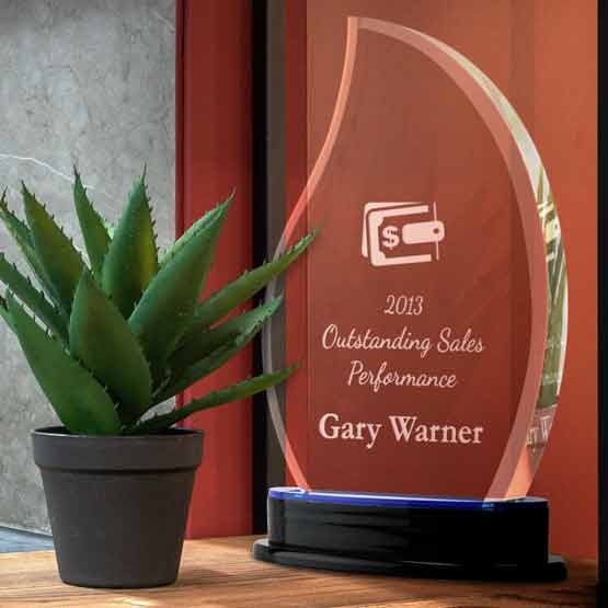 Custom Flame Shaped Acrylic Award For Sales With Logo And Name And Blue Mirror Base On Wood Shelf With Potted Plant
