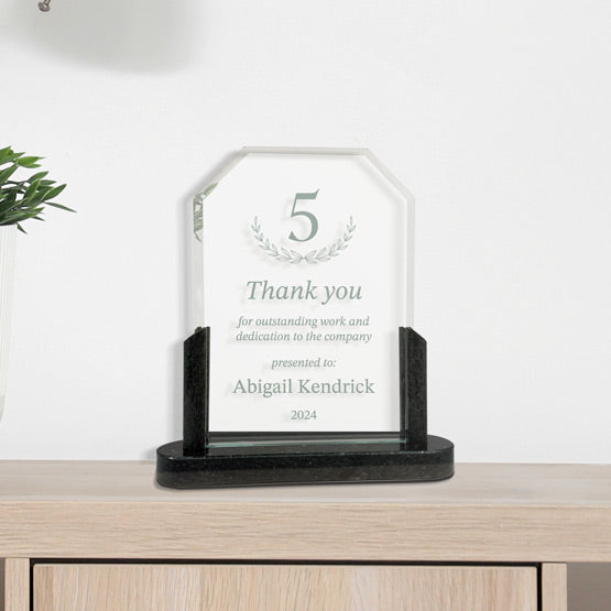 Custom Glass Award With Clipped Corners And Employee Thank You Message On Black Marble Base Displayed On Wood Dresser