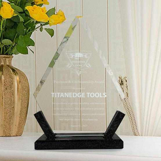 Custom Diamond Shaped Glass Award For Craftsmanship With Black Marble Base On White Shelf Beside Potted Flowers