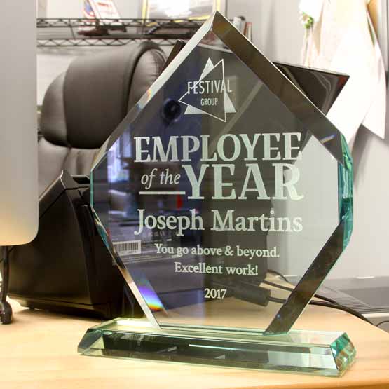Custom Diamond Glass Award For Employee Of The Year With Faceted Edges And Glass Base On Work Desk With Phone And Laptop