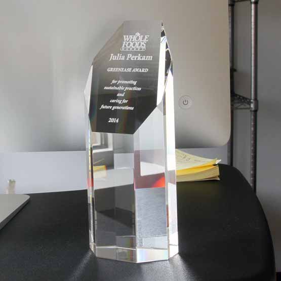 Custom Faceted Octagon Glass Tower Award For Sustainable Employee With Whole Foods Logo On Black Work Desk With Laptop