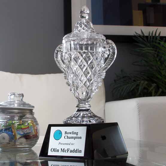 Custom Glass Award For Bowling Champion With Ornate Trophy Cup Shape And Black Base On Glass Coffee Table With Candy Jar