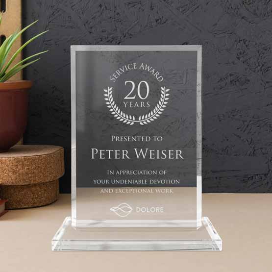 Custom Faceted Rectangle Glass Award For Years Of Service With Logo And Name And Glass Base On A Wood Desk With Potted Plant