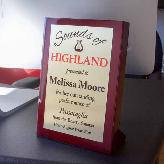 Custom Rosewood Piano Finish Plaque Award For Outstanding Performance With Gold Metal Plate On A Work Desk With Computer
