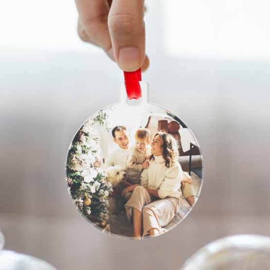 Hand Holding Up A Custom Ball Shaped Acrylic Ornament With Full Color Family Photo Via Red Ribbon