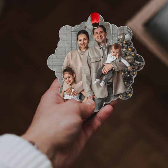 Hand Holding Custom Snowflake Shaped Acrylic Ornament With Red Ribbon And Full Color Photo Of Family With Christmas Tree