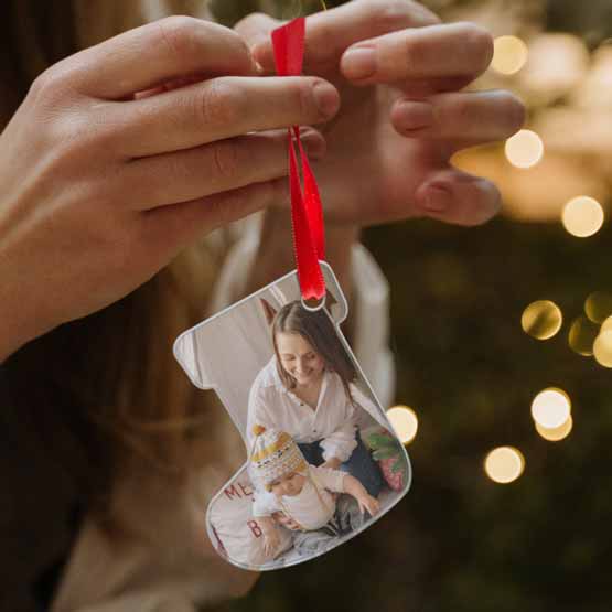 Hands Holding Custom Stocking Shaped Acrylic Ornament With Red Ribbon And Full Color Festive Photo Of Mom With Child