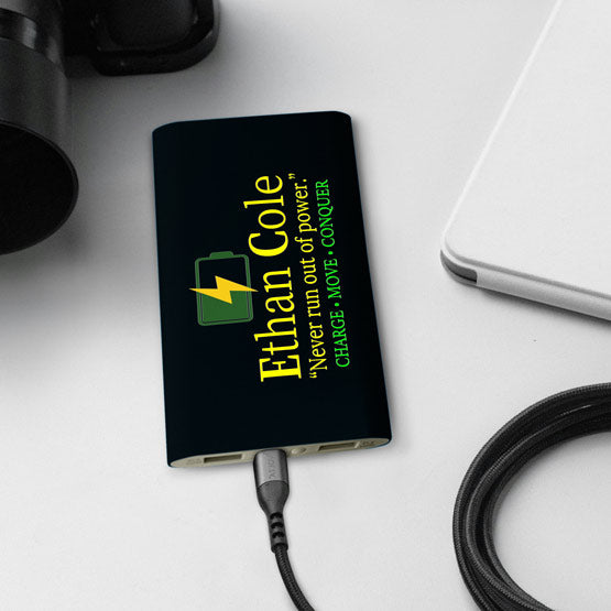 Black Aluminum Power Bank Custom Printed With Logo And Name And Motto Charging A Laptop Via USB C Cable On Office Desk