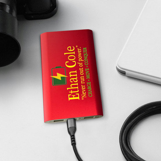 Red Aluminum Power Bank Custom Printed With Logo And Name And Motto Charging A Laptop Via USB C Cable On Office Desk