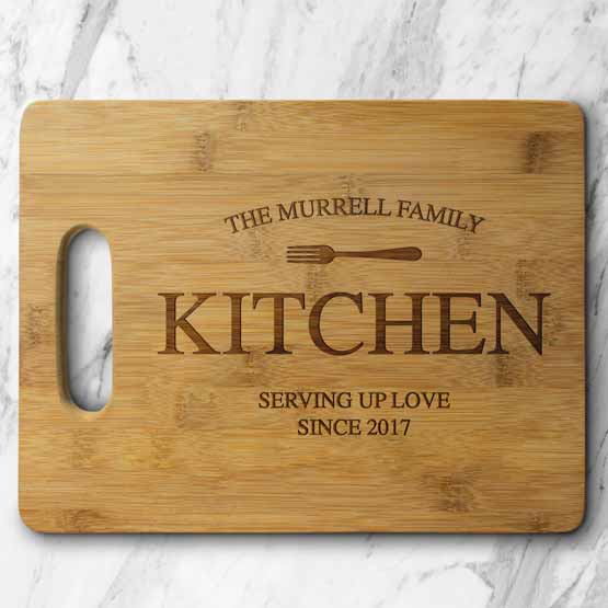 Custom Bamboo Cutting Board Engraved With Fork Art And Family Name And Date Sitting On Marble Kitchen Counter