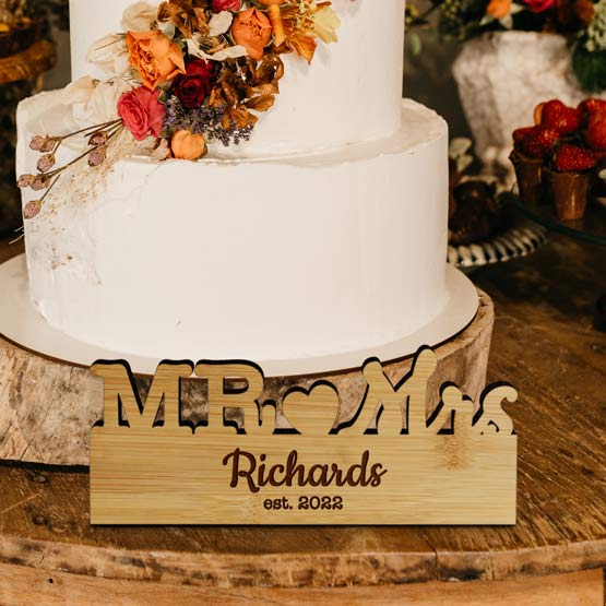 Custom Freestanding Bamboo Sign With Mister And Missus Cutout And Family Name And On Table With Wedding Cake And Strawberries