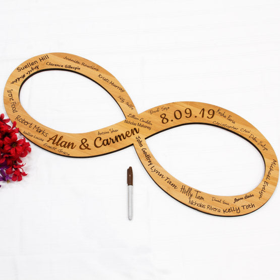 Custom Bamboo Sign With Infinity Symbol Shape And Engraved With Names And Date And Signed By Guests On Table With Flowers