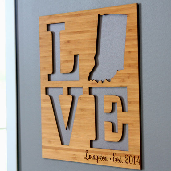 Custom Bamboo Sign With Unique State Shape Inside Love Cutout And Engraved With Name And Date Hanging On Office Wall