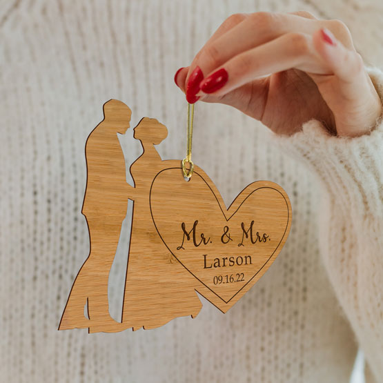 Woman Hand Holding Custom Bamboo Ornament With Couple Cutout On Heart Shape Engraved With Married Titles And Name