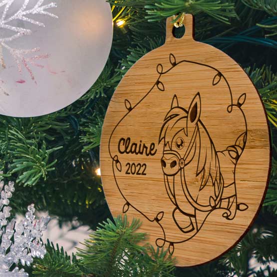 Custom Circle Bamboo Ornament Engraved With Cute Pony Artwork And Kids Name And Christmas Lights Hanging On Christmas Tree