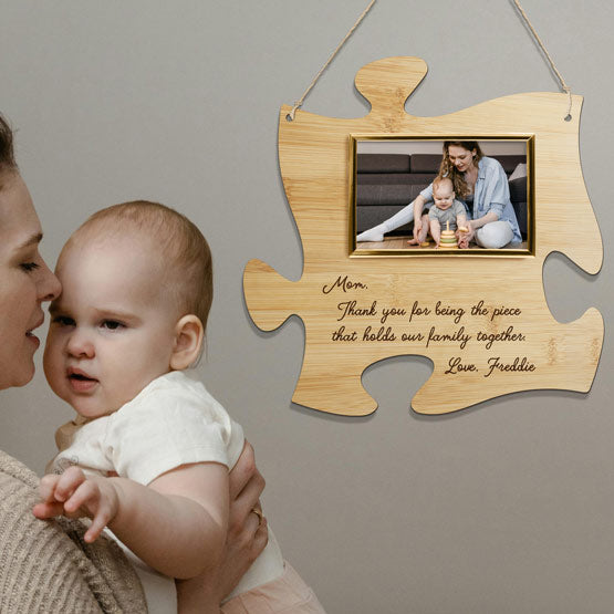 Mom Holding Newborn Beside Custom Puzzle Piece Bamboo Sign With Photo Of Them And Mom Appreciation Text Hanging On Wall