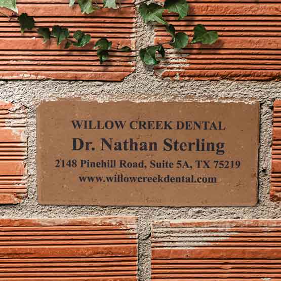 Custom Paver Brick Laser Engraved With Dental Office Address And Doctor Name Sitting In Wall With Matching Bricks