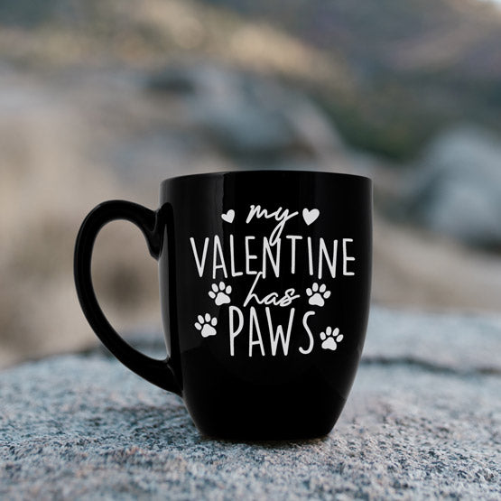 Custom Black Ceramic Bistro Mug Engraved With Hearts And My Valentine Has Paws Text Sitting On A Boulder Outside