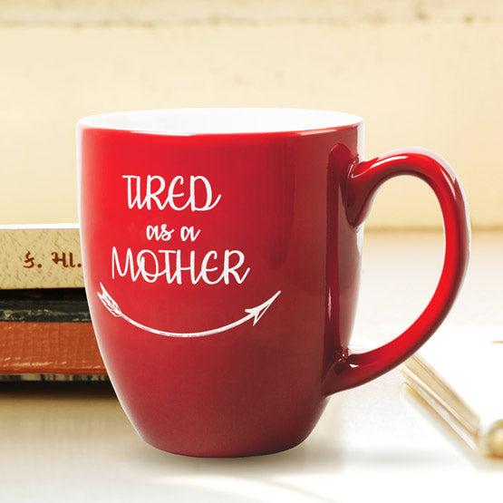 Custom Red Ceramic Bistro Mug Engraved With Tired As A Mother Text And Arrow Artwork Sitting On A Shelf With Books