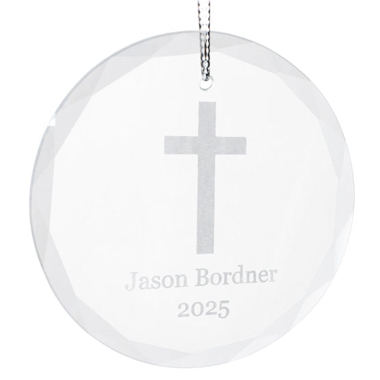 Circle Glass Christmas Ornament With Silver String And Engraved With Cross Art And Name And Year Against White Background