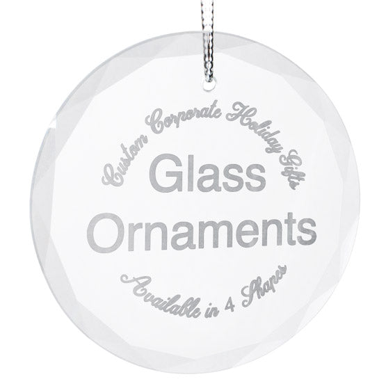 A round clear glass ornament with a silver string, featuring frosted text that reads 'Custom Corporate Holiday Gifts,' 'Glass Ornaments,' and 'Available in 4 Shapes' on a white background.