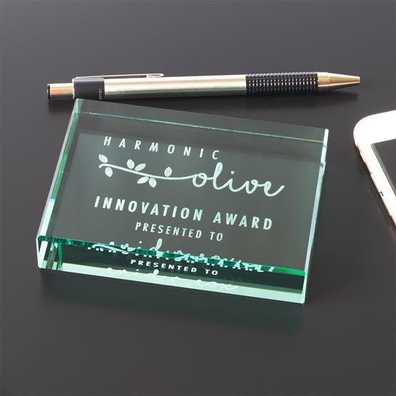 Custom Glass Paperweight Engraved With Logo And Innovation Award Message And Name On Office Desk With Pen And Laptop