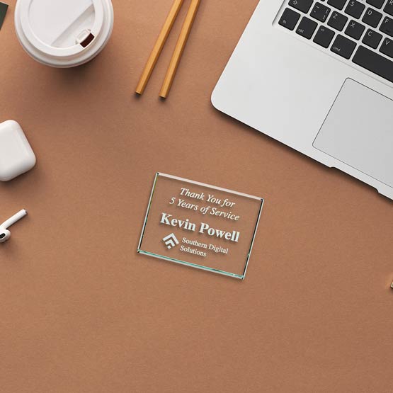 Custom Rectangle Glass Paperweight Engraved With Years Of Service Appreciation Message Sitting On Work Desk With Laptop