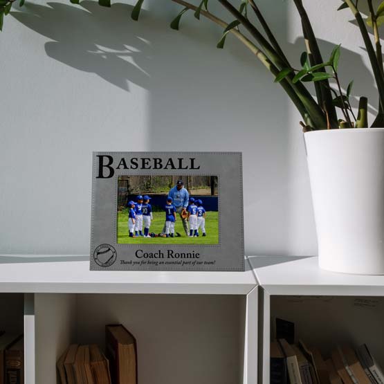 Custom Gray Faux Leather Picture Frame Engraved With Baseball Text And Photo Of Coach With Team On Shelf With Plant