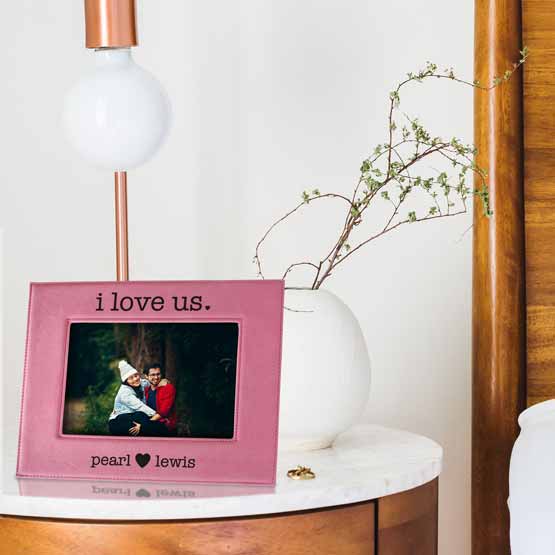 Custom Pink Faux Leather Picture Frame With Couple Photo And I Love Us Text On Night Stand With Ring And Lamp And Plant