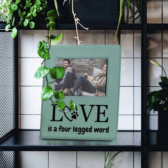 Teal Faux Leather Picture Frame With Photo Of Couple And Dog And Engraved With Love Message On Bookshelf With Plants