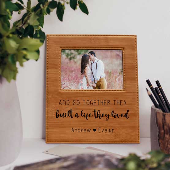 Wood Pattern Faux Leather Picture Frame With Couple Photo And Engraved With Built A Life Message On Shelf With Plant