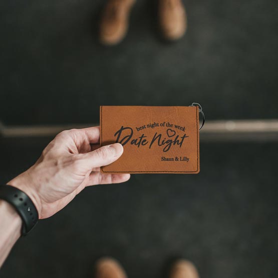 Man Hand Holding A Custom Rawhide Faux Leather Wallet Laser Engraved With Best Night Of The Week Date Night Text And Names
