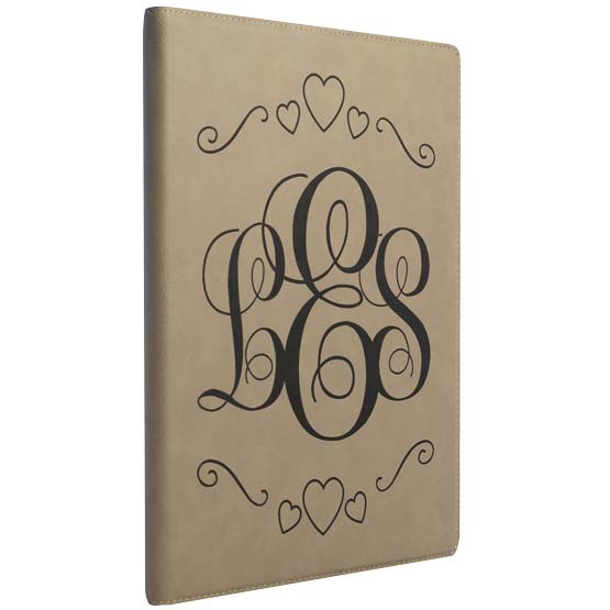 Custom Light Brown Faux Leather Notebook Laser Engraved With Ornate Initials And Heart Artwork Against A White Background