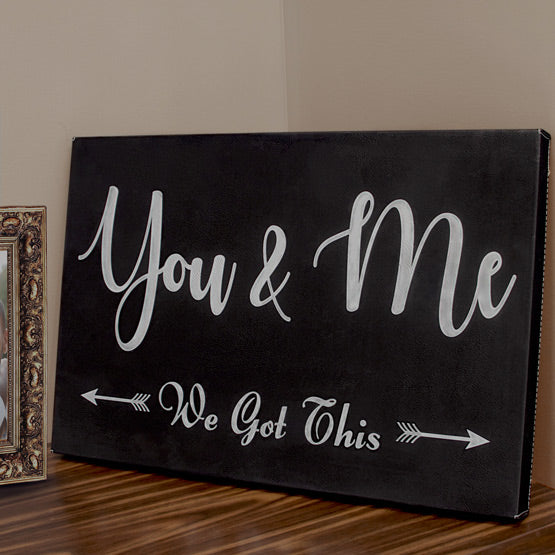 Black Faux Leather Wrapped Rectangle Canvas Engraved With You And Me We Got This Text And Arrow Art On Shelf With Photo Frame