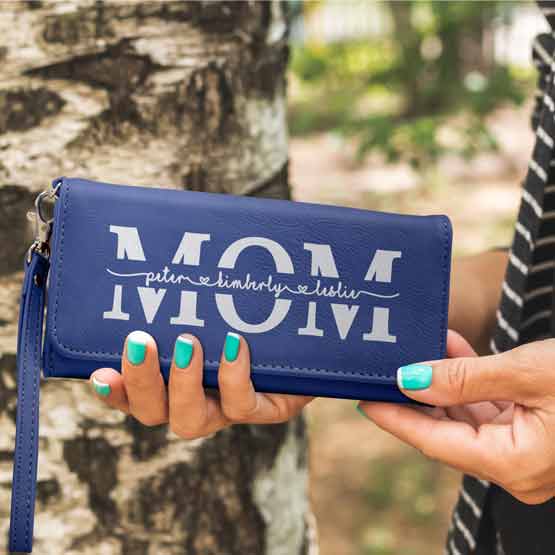 Woman Hands Outdoors Holding Blue Faux Leather Trifold Wallet With Wrist Strap And Engraved With Mom And Family Names
