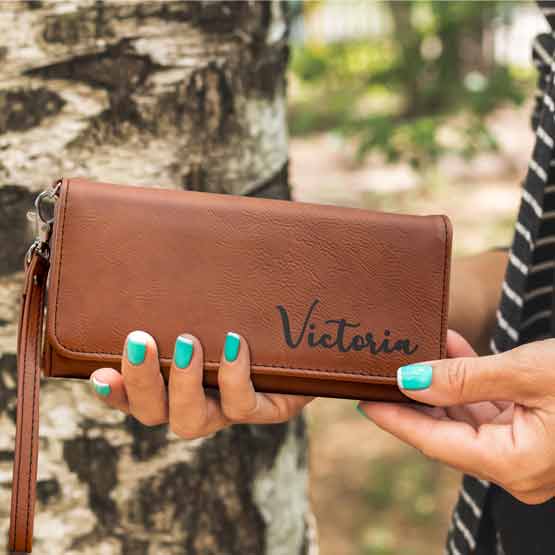 Woman Hands Outdoors Holding Custom Rawhide Faux Leather Trifold Wallet With Wrist Strap And Laser Engraved With Name