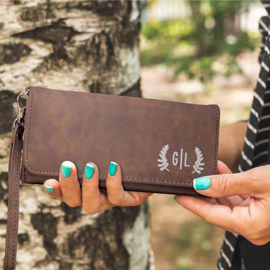 Woman Hands Outdoors Holding Custom Rustic Faux Leather Trifold Wallet With Wrist Strap And Laser Engraved With Initials
