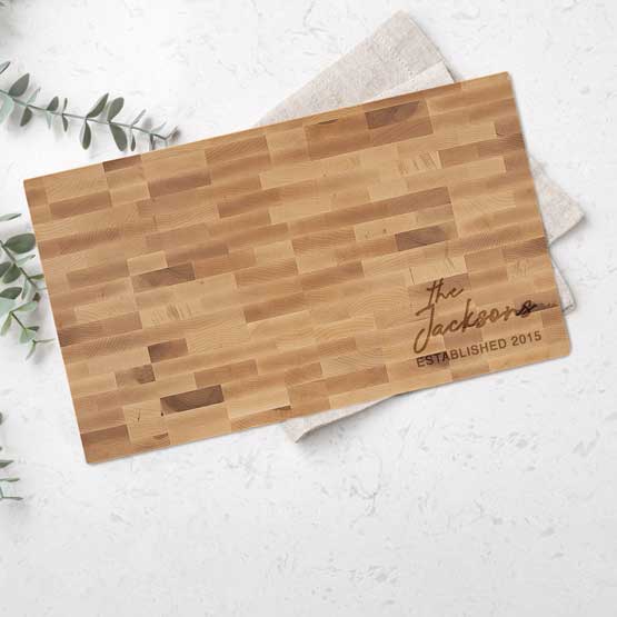 Custom Maple Wood Butcher Block Cutting Board Laser Engraved With Family Name And Date On Counter With Plant And Hand Towel