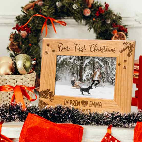 Red Alder Picture Frame With Snowy Couple Photo And Engraved With Our First Christmas Details On Table With Festive Decor
