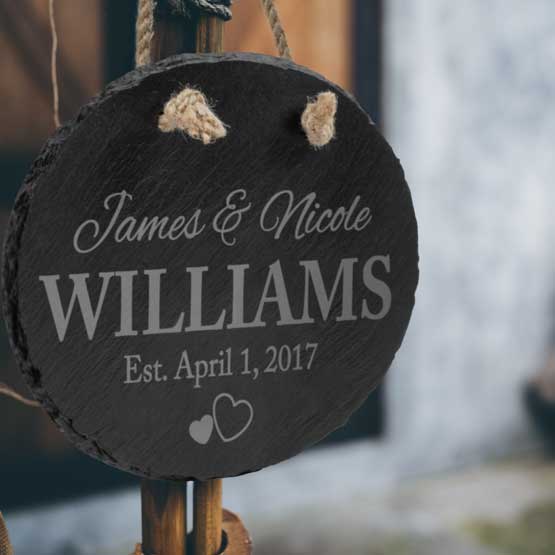 Custom Slate Oval Sign Printed With Names And Date And Hearts Hanging Outside On Wooden Post Via Rope