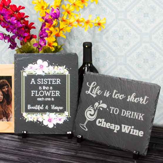 Two Slate Rectangle Signs With Sister Message And Fun Wine Message Standing On Shelf Via Plastic Stands By Flowers And Frame