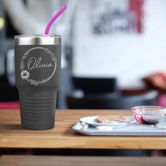 Gray Thirty Ounce Stainless Steel Coffee Tumbler With Straw And Engraved With Name And Flower Art On Table With Food Platter