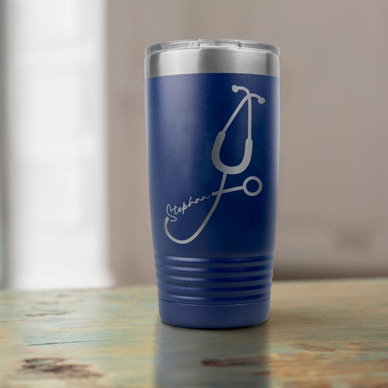 Navy Blue 20 Ounce Stainless Steel Tumbler Laser Engraved With Custom Name Inside Stethoscope Art On Wood Table