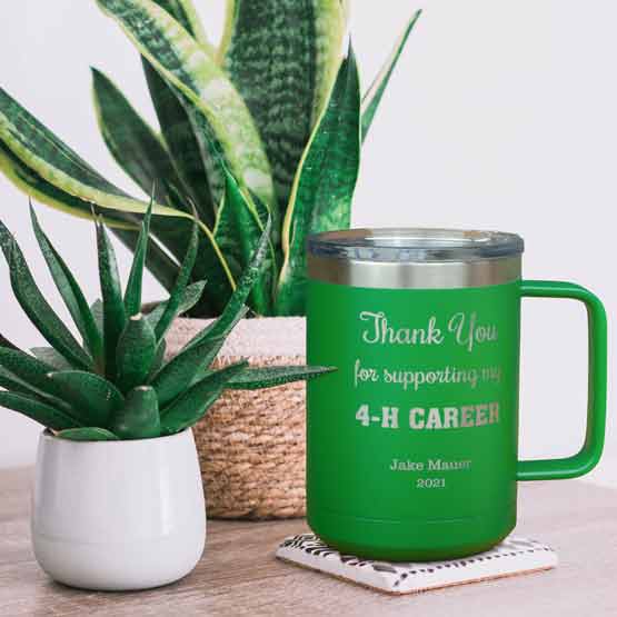Green Stainless Steel 15 Ounce Tumbler Mug Engraved With Thank You Message And Name And Year On Table With Potted Plants