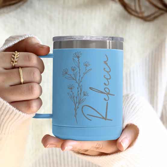 Woman Hands Holding Light Blue Stainless Steel Coffee Tumbler Mug With Handle And Engraved With Name And Flower Art