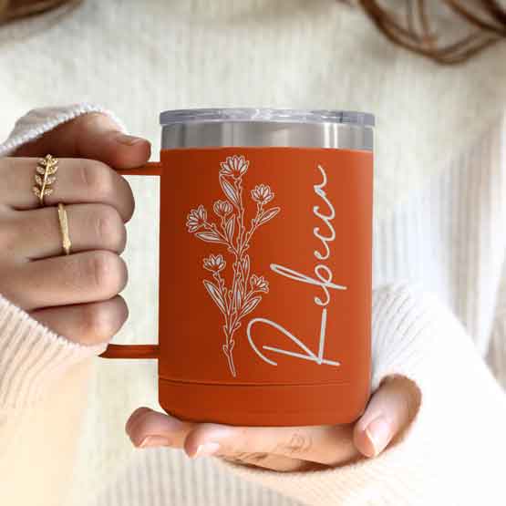 Woman Hands Holding Orange Stainless Steel Coffee Tumbler Mug With Handle And Engraved With Name And Flower Art