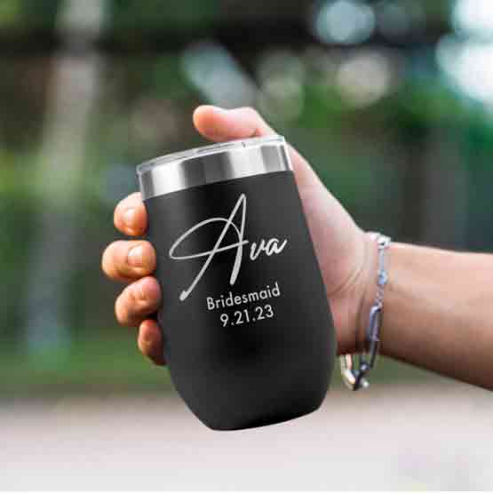 Woman Hand Outdoors Holding Custom Black Stemless Wine Tumbler Engraved With Name And Date And Bridesmaid Text