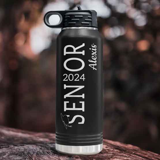 Black 32 Ounce Water Bottle Laser Engraved With Graduation Hat On Senior Text And Year And Name Sitting On Log Outdoors